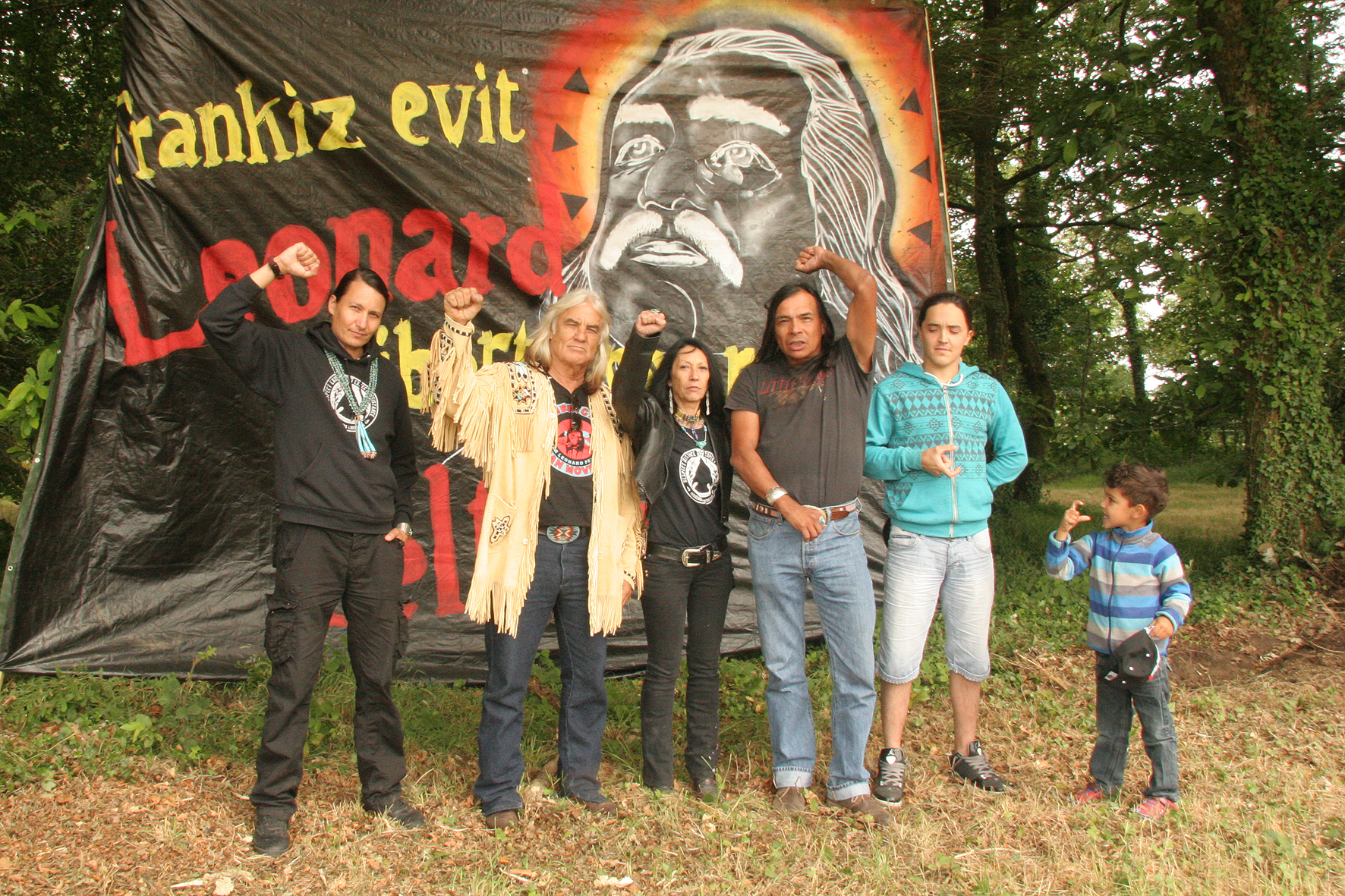 Amérindiens, le poing levé, devant une bâche réclamant la libération de Leonard Peltier au festival.